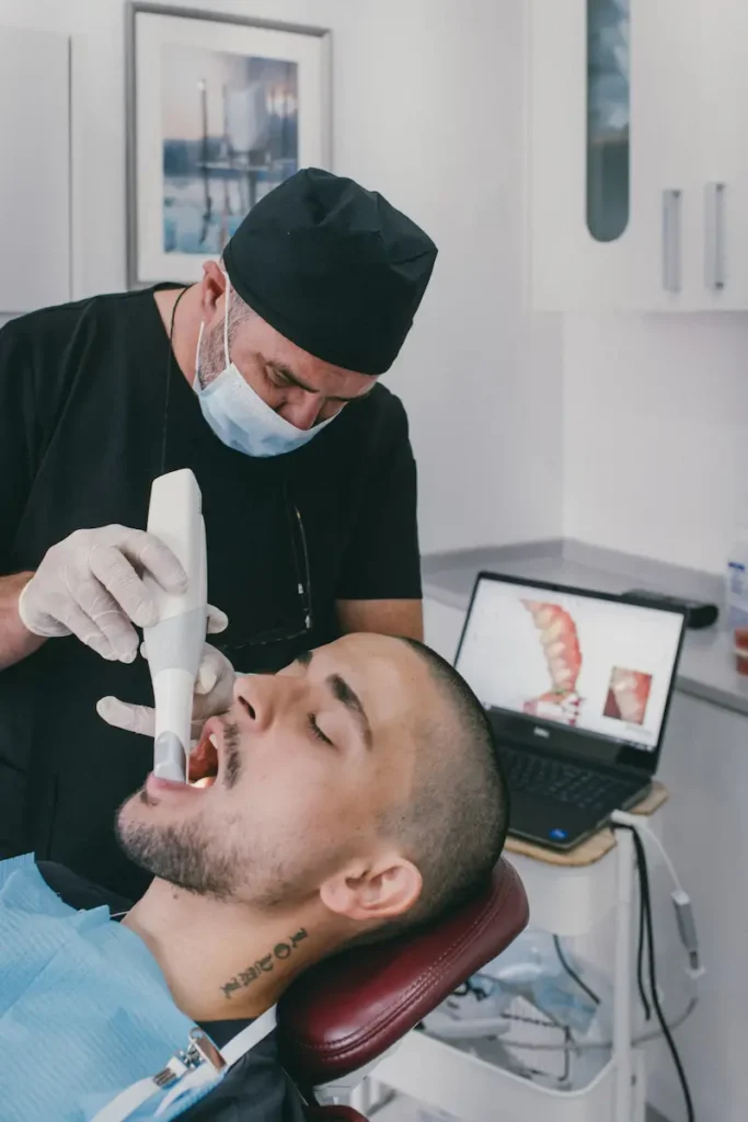 Dentista a realizar uma consulta odontológica ao paciente, usando um aparelho para tratamento dental, com equipamento digital e cenário clínico moderno.
